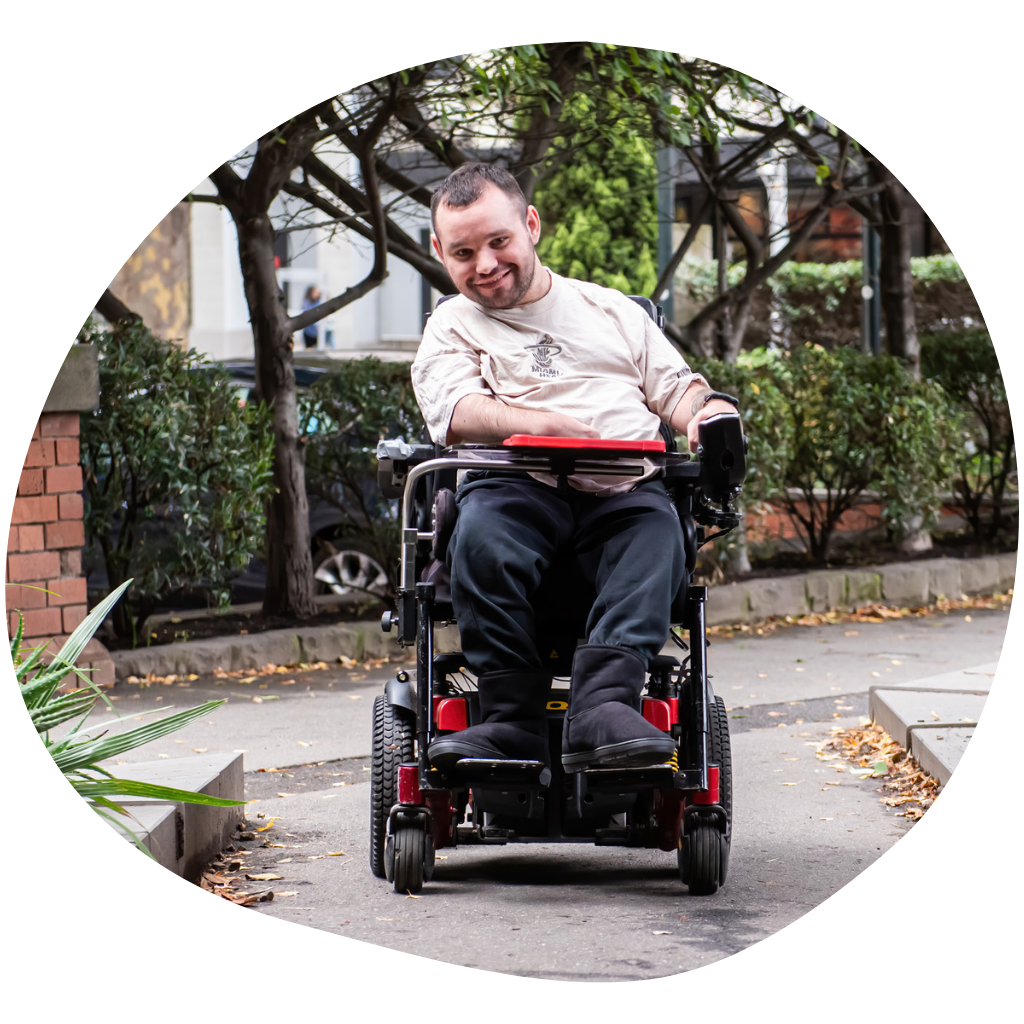 Jono is heading down a pathway in his wheelchair in the city